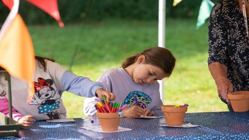Two young girls crafting with colour pens in an gazebo draped with bunting